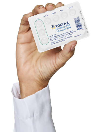 A hand with a white sleeve holding a blister pack